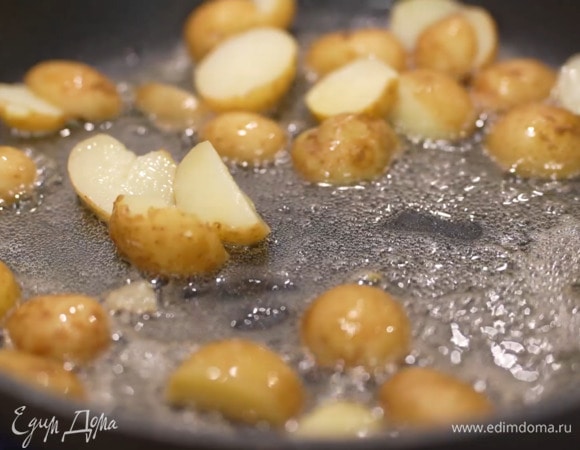 Разогреть в сковороде 1 ст. ложку оливкового масла и сливочное масло, выложить половинки картофеля и измельченный чеснок, посолить и обжаривать до появления золотистой корочки.