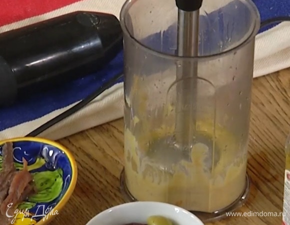Приготовить заправку: оставшийся зубчик чеснока и желток выложить в чашу для взбивания, добавить горчицу, 3–4 анчоуса, выжатый из половинки лимона сок, оливковое масло Extra Virgin, посолить и взбить все погружным блендером. Затем влить 1–2 ст. ложки кипяченой воды и все перемешать.