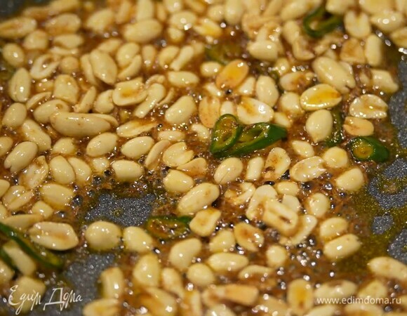 Разогреть в сковороде растительное масло, выложить арахис, посыпать его зирой, кайенским перцем, посолить, добавить перец чили, все перемешать и обжарить, затем влить сироп, перемешать и еще немного обжарить.