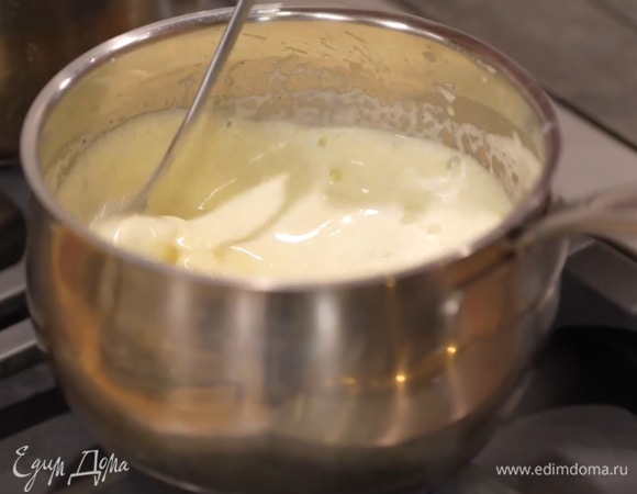 Желтки с оставшейся сахарной пудрой взбить блендером с насадкой-венчиком в плотную массу, продолжая взбивать, тонкой струйкой влить горячее молоко, затем перелить в сотейник и, непрерывно помешивая, заваривать на маленьком огне, пока масса не загустеет.