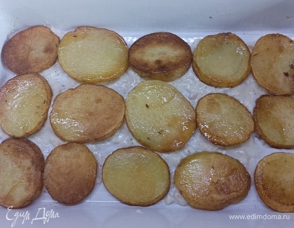 Дно формы для запекания слегка смазать соусом и выложить в один слой жареный картофель.