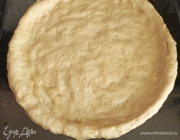 Готовое тесто распределите руками на противне, формируя лепешку с бортиками.