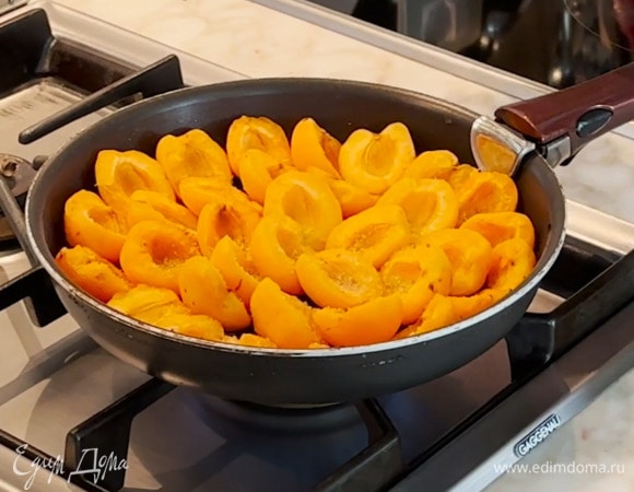 В сковороду с карамелью плотно уложить половинки абрикосов срезами вверх и посыпать оставшимся сахаром.