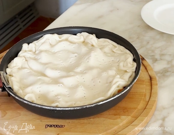 Накрыть абрикосы тестом, немного присобрав его по краям, и часто наколоть вилкой.