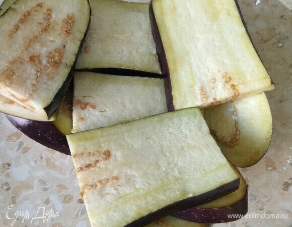 Баклажаны вымыть, очистить от хвостиков, разрезать вдоль на ломтики толщиной 1 см, посыпать солью и оставить на 10 минут, чтобы они дали сок.