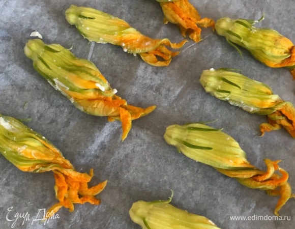 Цветки цукини промыть, промокнуть бумажным полотенцем и, удалив сердцевину, наполнить начинкой, а затем выложить на противень, выстеленный бумагой для выпечки.