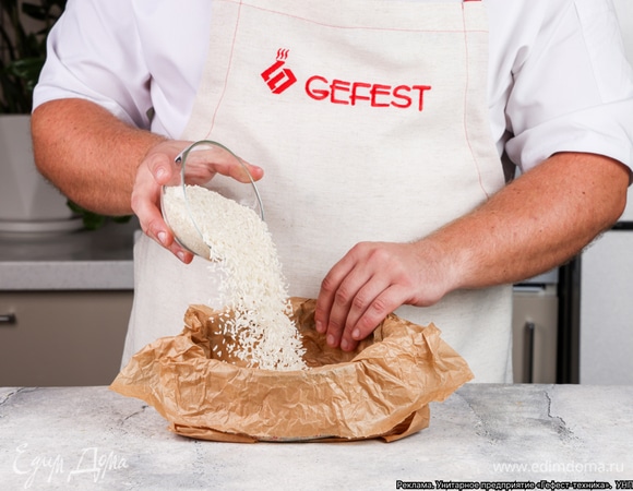 Накройте тесто еще одним пергаментом для выпечки, насыпьте сверху 150 г риса.