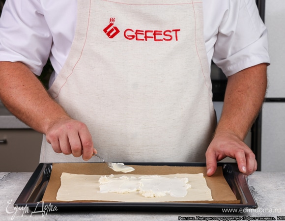 Застелите противень бумагой для выпечки, положите сверху тесто и смажьте его творожным сыром.