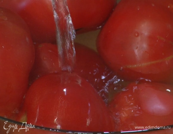 Помидоры надрезать крестиком с обратной стороны плодоножки, выложить в глубокую миску, залить кипятком и дать немного постоять.