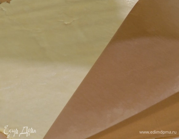 Поместить тесто между двумя слоями бумаги для выпечки, раскатать в тонкий пласт и отправить в холодильник примерно на 20 минут.