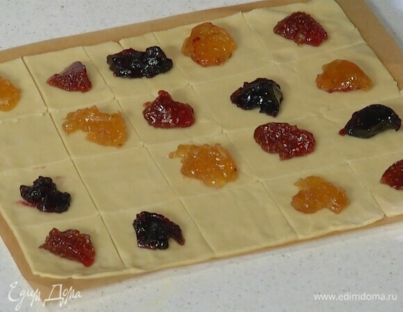 Нарезать тесто на бумаге для выпечки небольшими квадратами, в центр каждого выложить по 1 ч. ложке джема и свернуть в трубочки или сложить конвертиками.