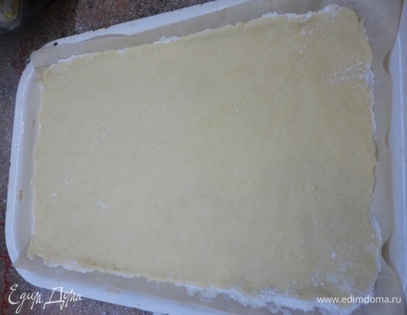 Раскатываем тесто в два прямоугольника толщиной 4–5 мм сразу на пергаменте для выпечки. Подравниваем края (подрезаем, выпекаем отдельно и измельчаем в крошку для финальной посыпки) и накалываем тесто вилкой.