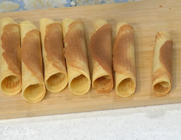 Разогреть вафельницу, испечь вафли, сразу свернуть их в трубочки и дать остыть.