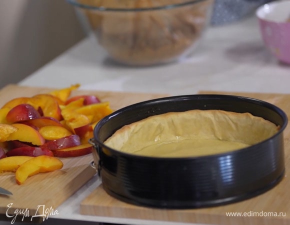 Дно разъемной формы выстелить бумагой для выпечки и равномерно распределить тесто, сформировав невысокие бортики. Сверху поместить еще лист бумаги для выпечки, засыпать любыми бобовыми и выпекать корж в разогретой духовке 12–15 минут.