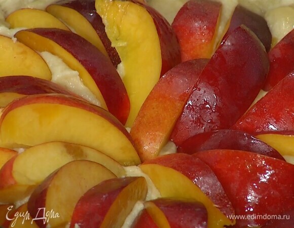 Удалить бумагу с бобовыми с подпеченного коржа, равномерно выложить франжипан и утопить в нем дольки нектарина.