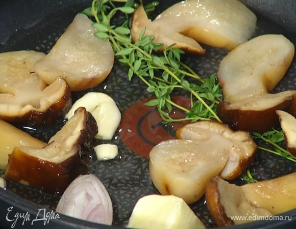 Разогреть в отдельной сковороде оставшееся оливковое и 1 ст. ложку сливочного масла, выложить половину веточек тимьяна, чеснок, половинку шалота, размороженные белые грибы и обжарить до золотистой корочки.