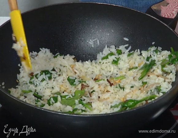 Шпинат выложить в сковороду к луку с чесноком и полить лимонным соком, затем добавить готовый рис и все перемешать.
