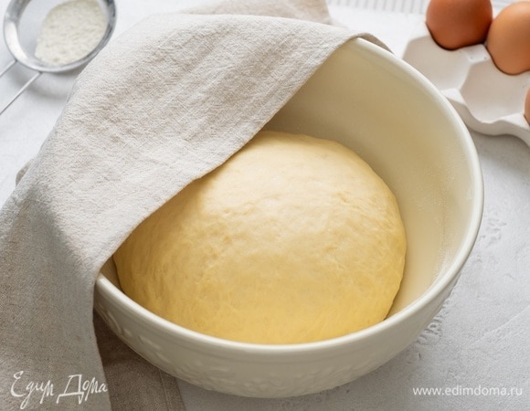 Уберите тесто в чистую миску, слегка припыленную мукой. Накройте заготовку влажным полотенцем и оставьте в теплом месте без сквозняков на 1,5 часа.