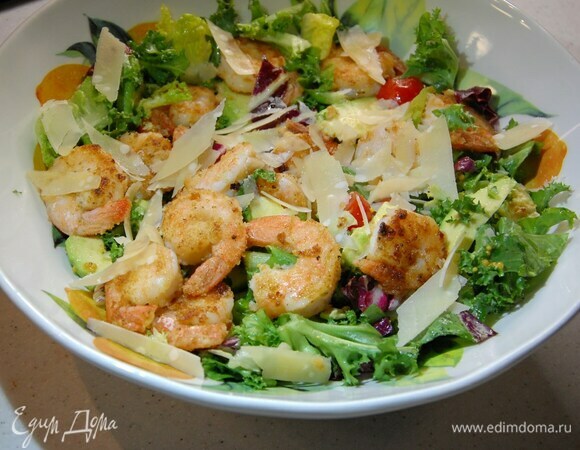 Теплые креветки выложить на салат и посыпать хлопьями сыра.