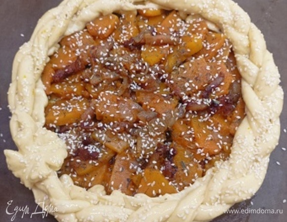 Сплетаем из тонких полосок косичку (это полностью по вашему желанию, можно обойтись и без этого декора). Смазываем бортики смесью желтка и молока (1 ст. л.), выкладываем на них косичку, которую также смазываем и посыпаем кунжутом. Выпекаем пирог в разогретой до 180°С духовке в течение 40–45 минут до золотистой корочки.