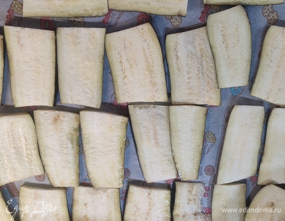 Баклажаны нарезать слайсами. Выложить на противень. Запечь в духовке 20 минут при температуре 200°C.