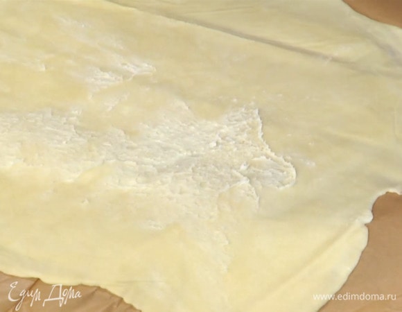Раскатать тесто между двумя листами бумаги для выпечки в тонкий пласт.