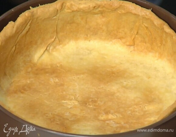 Дно разъемной формы выстелить бумагой для выпечки, выложить тесто, сформировав высокие бортики, и часто наколоть его вилкой. Сверху поместить лист бумаги для выпечки, засыпать любыми бобовыми и выпекать в разогретой духовке 35 минут.