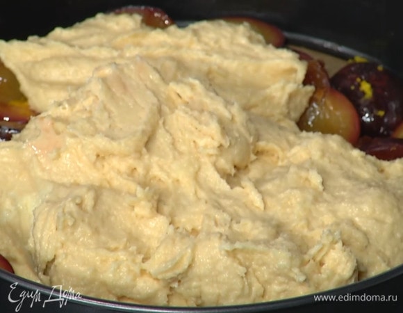 Дно разъемной формы выстелить бумагой для выпечки, переложить запеченные сливы (сироп в форме сохранить!), сверху выложить тесто и равномерно распределить тонким слоем.