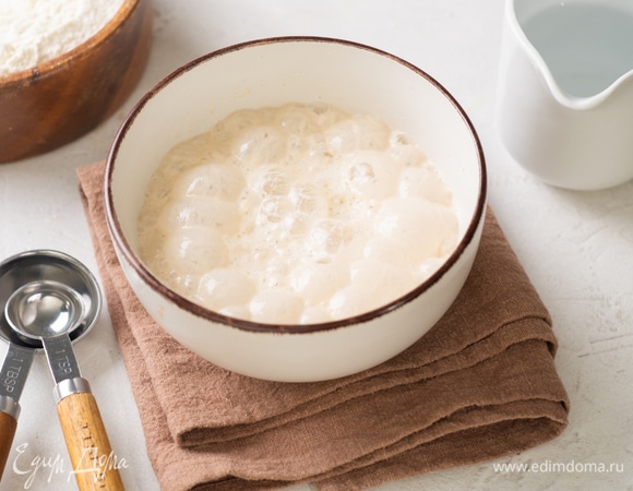 Приготовьте опару для дрожжевого теста. В теплую воду просейте 2 столовых ложки муки, добавьте 1 столовую ложку сахара, все перемешайте. Всыпьте дрожжи и все перемешайте. Накройте миску крышкой или полотенцем и уберите в теплое место на 20–30 минут.