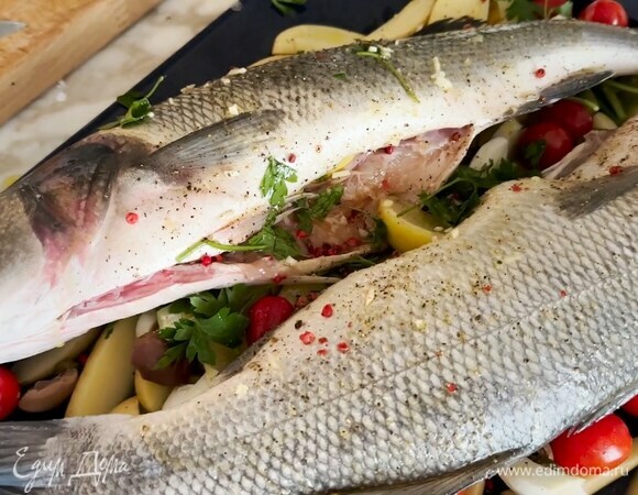 Тушки сибаса поместить на овощи, полить оливковым маслом, посыпать розовым и черным перцем.