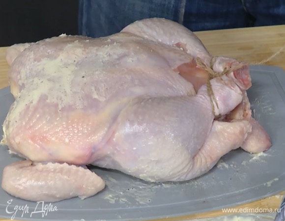 Предварительно размягченное сливочное масло перемешать с солью и перцем и смазать курицу под кожей и снаружи, затем кулинарной нитью связать ножки и переложить тушку в жаропрочную форму грудкой вниз.