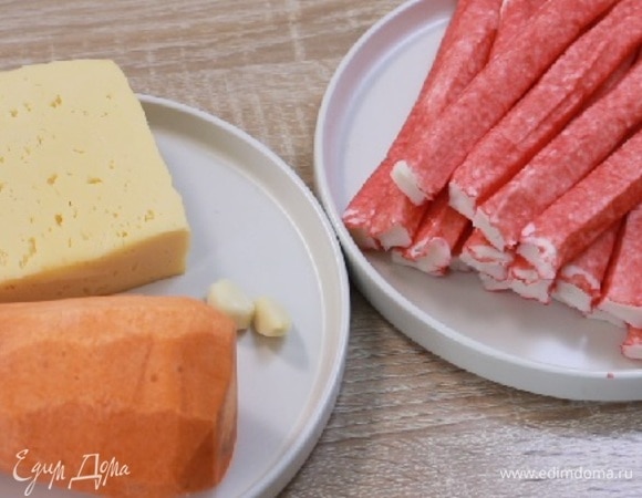 Подготовить крабовые палочки, которые можно развернуть в пласт, и сыр твердых сортов. Крабовые палочки полностью разморозить. Морковь и зубчики чеснока очистить и промыть. 