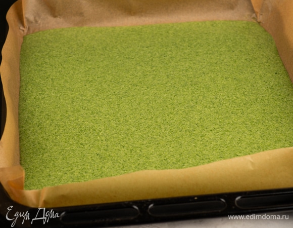 Бисквитное тесто вылейте на противень и разровняйте лопаткой. Поместите в духовку на второй уровень сверху. Выпекайте бисквит 25 минут до румяного цвета.