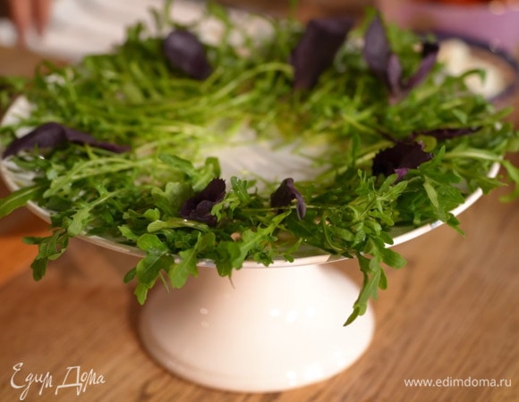 Большое блюдо полить ближе к краям небольшим количеством оливкового масла Extra Virgin, центральную часть смазать соусом, сверху разложить веером руколу, сбрызнуть ее оливковым маслом и посолить, затем выложить листья лилового и зеленого базилика.м