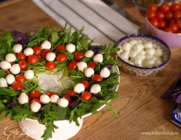 Черри разрезать пополам и выложить на зелень срезами вниз, сбрызнуть оливковым маслом и бальзамическим уксусом, между помидорами разложить шарики моцареллы.