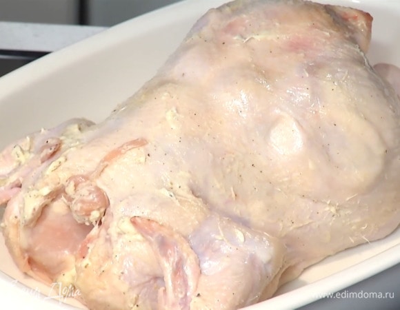 Один апельсин разрезать на 4 части, вложить внутрь тушки и, связав ножки кулинарной нитью, выложить ее грудкой вниз в жаропрочную керамическую форму.