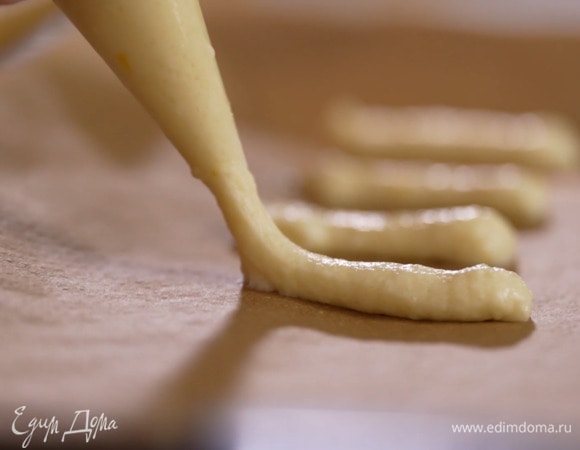 Переложить тесто в кондитерский мешок и отсадить на выстеленный бумагой для выпечки противень небольшие полоски.