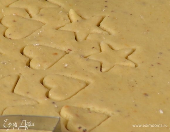 Рабочий стол присыпать оставшейся мукой, раскатать отдохнувшее тесто в пласт толщиной полсантиметра, кондитерскими формочками вырезать фигурки разного размера и выложить на выстеленный бумагой для выпечки противень.