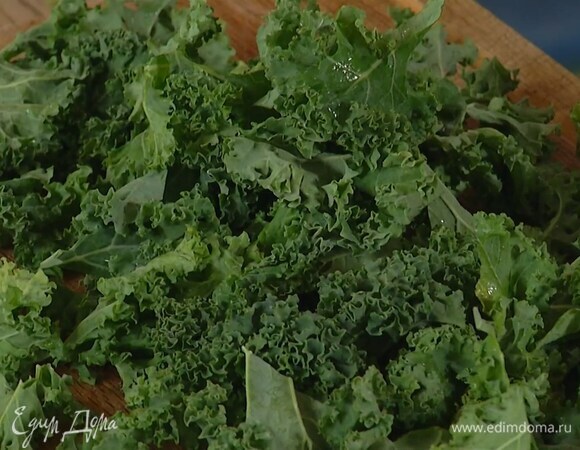 Листья кейла, вырезав грубые стержни, добавить в сковороду, все посолить, перемешать и томить на маленьком огне под крышкой пару минут.