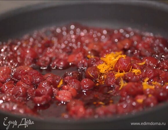 Размороженную вишню, слив жидкость, выложить на сковороду, посыпать сахаром, добавить цедру и сок апельсина, все перемешать, затем влить вино и дать алкоголю выпариться на сильном огне.