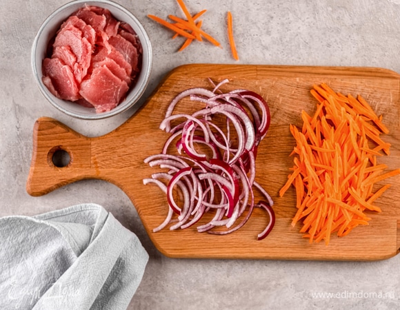Нарежьте лук тонкими полукольцами, а морковь — соломкой. Обжарьте кусочки мяса вместе с овощами на сильном огне до золотистой корочки.