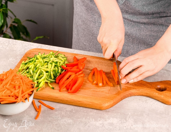 Подготовьте овощи: очистите морковь от кожуры и нарежьте тонкой соломкой, натрите огурец на средней терке, болгарский перец нарежьте соломкой.