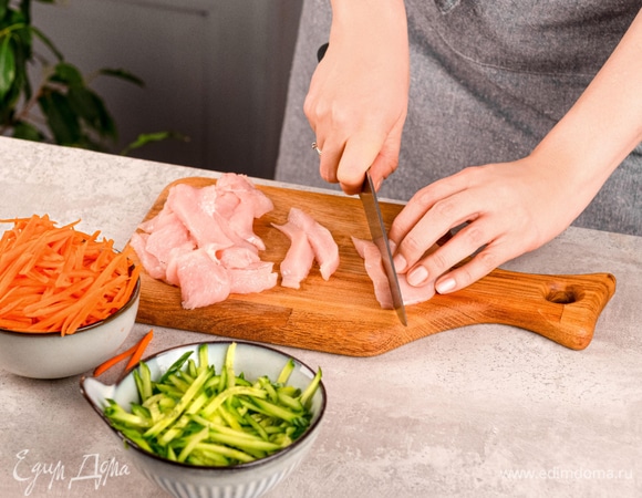 Нарежьте куриное филе тонкими полосками вдоль волокон.