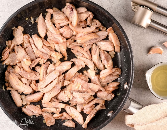 На сковороде обжарьте измельченный чеснок и добавьте курицу, обжаривайте около 2 минут.