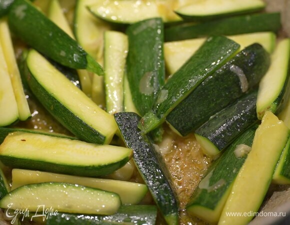 Цукини нарезать небольшими брусками, добавить к луку с чесноком и обжаривать до появления румяной корочки, затем посолить и перемешать.