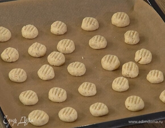 Сформировать из теста небольшие шарики, выложить их на выстеленный бумагой для выпечки противень и слегка прижать вилкой.