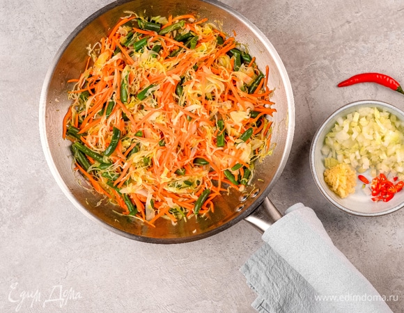 На сильном огне обжарьте на сковороде морковь, капусту и фасоль до готовности. Добавьте перец чили, лук и чеснок и обжарьте их еще 1–2 минуты.