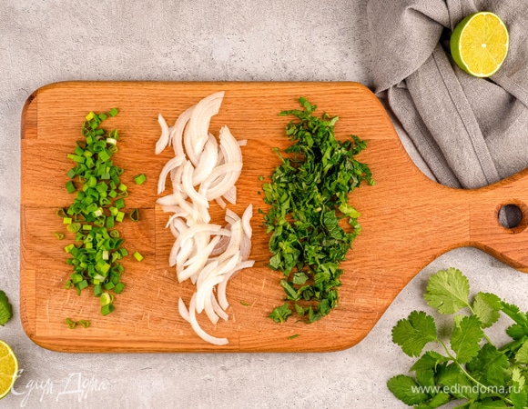 Вымойте кинзу и мяту, мелко порубите их. Зеленый лук нарежьте колечками, а 1/2 репчатого — тонкими кольцами.