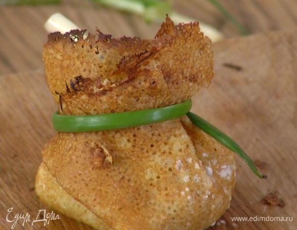 В центр каждого блина выложить немного начинки, собрать края в мешочек и завязать перьями зеленого лука.