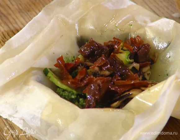 Уложить тесто в плоские тарталетки, так чтобы края свешивались, разложить зеленый соус, цукини и баклажаны, вяленые помидоры, обжаренный лук и накрыть начинку краями теста.